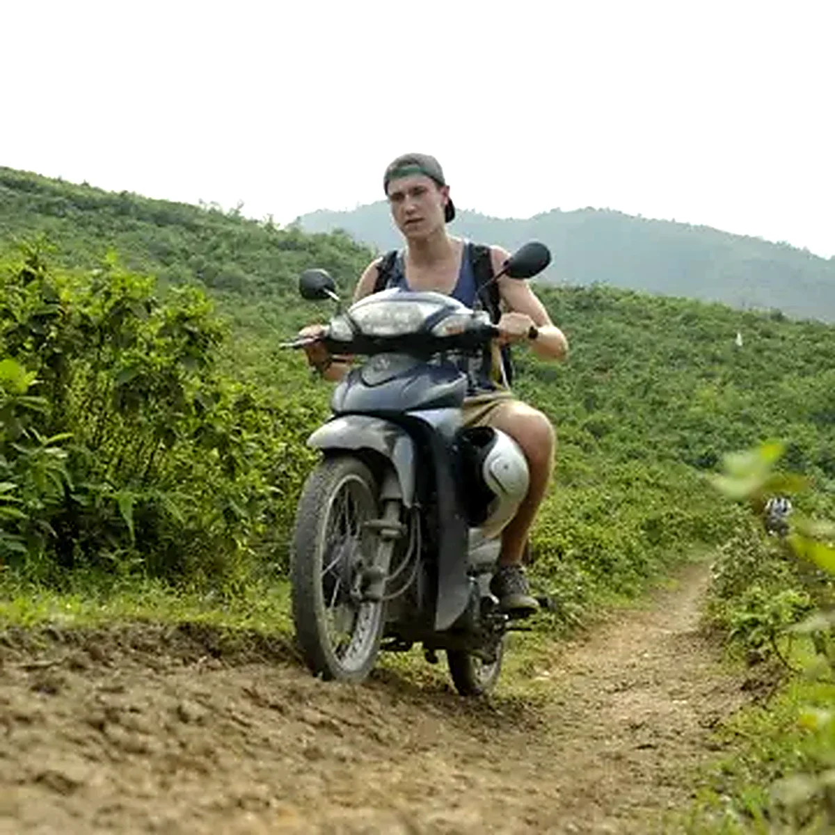 Man riding a motorbike along a muddy trail through the Vietnamese highlands