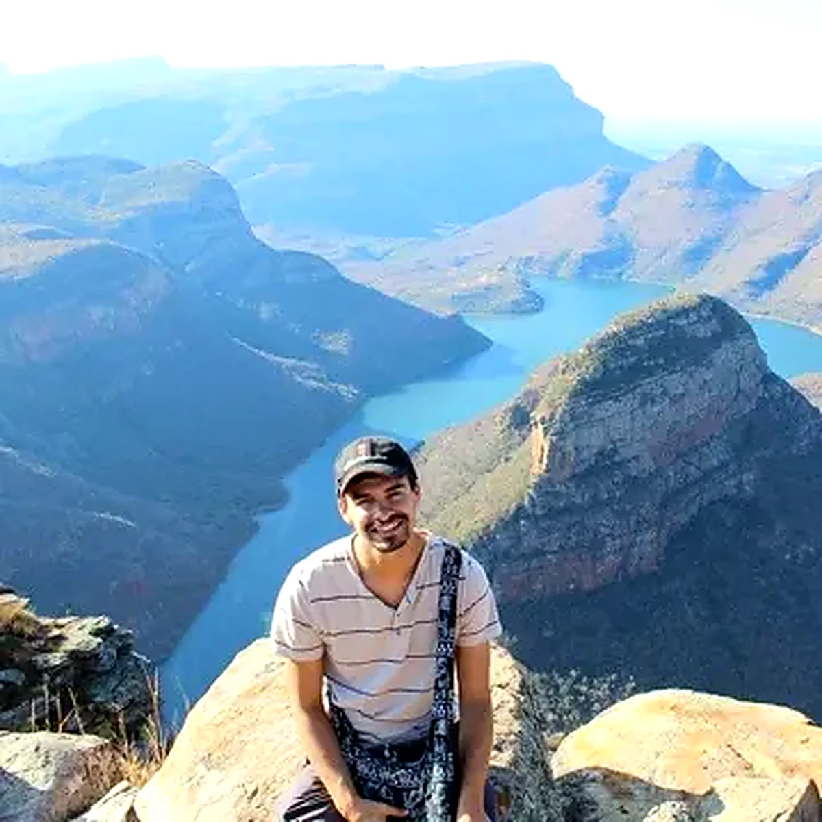 Man sitting on a cliff edge overlooking Blyde River Canyon and its turquoise reservoir